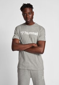 Grijze katoenen t-shirt met korte mouwen, met een witte "hummel" logo op de borst. Klassieke ronde hals, losse pasvorm, zachte textuur.