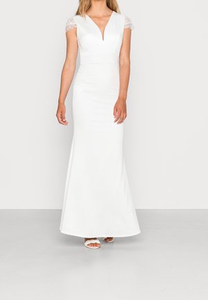 Witte avondjurk met een aansluitende silhouet, diepe V-hals en korte kanten mouwen. De stof heeft een gladde afwerking en valt tot op de grond.