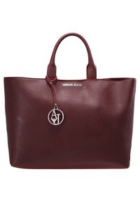 Burgundowa torba tote z imitacji skóry z dwoma uchwytami, czerwonym wykończeniem, logo marki oraz srebrnym charmsiem z inicjałami. Gładka tekstura i wyraźny kształt.