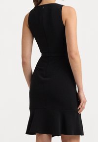 Czarna sukienka bez rękawów z dopasowanym gorsetem, rozkloszowanym dołem i subtelnym suwakiem z tyłu. Wykonana z gładkiego materiału o wyrafinowanym wykończeniu.