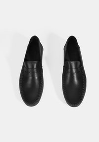 Zwarte leren loafers met een gladde afwerking, gestikte details en een ronde neus. Strak ontwerp zonder zichtbare hardware of versieringen.