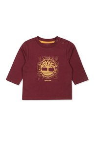 Bordowa koszulka z długim rękawem wykonana z bawełny, z żółtym wzorem graficznym drzewa i tekstem na środku, z zatrzaskami na ramieniu.