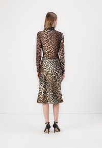 Sheer long-sleeve top and flared midi skirt in leopard print, featuring shades of brown and black, paired with black high-heeled shoes.
