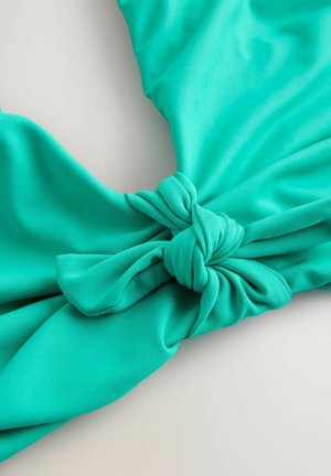 Tyrkysová textília s hladkou štruktúrou a uzlovým detailom. Dizajn má záhyby a živú farbu, vhodný na bežné nosenie.