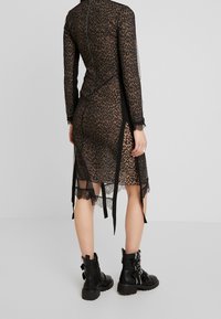 Svart leopardmönstrad klänning med långa ärmar, spetsdetaljer och sidfickor. Matchad med svarta ankelboots med spännen och texturerade sulor.