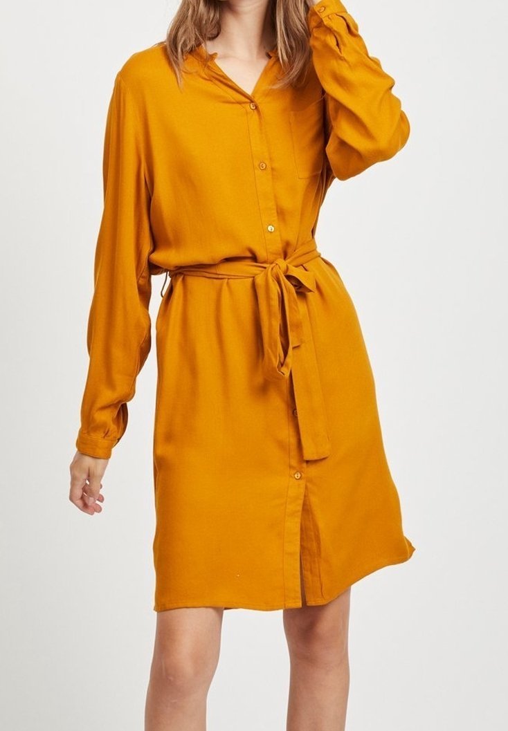 Robe chemise jaune moutarde avec manches longues, boutons sur le devant et ceinture à nouer à la taille. Tissu lisse avec une coupe décontractée.
