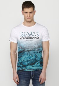 White short-sleeve T-shirt featuring a blue graphic design with wave patterns and bold black text. Cotton fabric with a round neck.