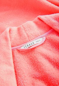 Korallenrosa Fleece-Stoff mit strukturierter Oberfläche; Etikett mit der Aufschrift "FÉRAUD PARIS" auf Satin-Finish mit rosa Umrandung aufgenäht.