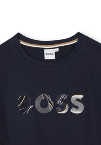 Marine T-shirt met een gestructureerd "BOSS" logo in verschillende patronen, aangevuld met een geribbelde rand in beige en wit. Zacht materiaal.