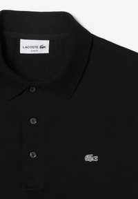 Polo Lacoste noir avec coupe slim, col côtelé, patte à trois boutons et petit logo crocodile brodé sur la poitrine.