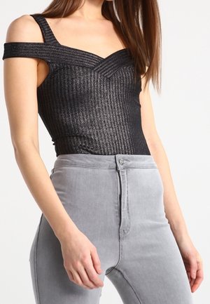 Black ribbed bodysuit with off-shoulder straps, featuring a v-shaped neckline. Paired with high-waisted light gray denim jeans.