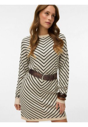 Helebeežist kleit pikkade varrukatega, helebeež värv, millel on mustad ševrontriibud. Viimistletud pruuni vöö ja sobivate tekstuuriga käevõrudega.