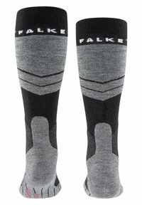 Calze al ginocchio nere e grigie con motivi a chevron, texture morbida, polsini a coste e dettagli rinforzati sulla punta. Nome del marchio "Falke" in evidenza.