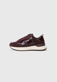 Sneaker marrone scuro con pannelli in suede e lucidi, allacciatura frontale, suola spessa bianca e linguetta sul tallone, mostrato in profilo laterale.