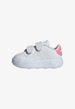 Zapatilla blanca con correas de velcro, detalles laterales perforados, punta redondeada y un acento rosa en el talón. Fabricada en material sintético.