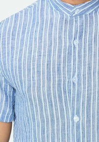 Chemise à manches courtes ray ée bleu clair en lin. Présente un col montant et des boutons à l'avant avec une finition en tissu texturé.