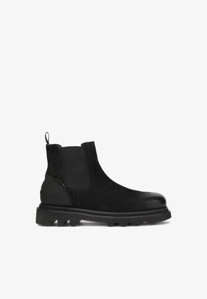 Bottines Chelsea noires avec un dessus en cuir lisse, des panneaux élastiques sur les côtés, une languette de tirage et une semelle en caoutchouc épaisse avec un détail cramponné.