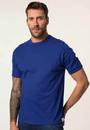 T-shirt in cotone blu royal con scollo rotondo, maniche corte, una texture liscia e una vestibilità regolare, abbinata a jeans di denim.