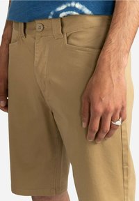 Khaki shorts van katoen, met een drukknopsluiting aan de voorkant, riemlussen en twee zijzakken. Glad textuur en gestroomlijnd ontwerp.