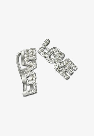 Une paire de boucles d'oreilles en argent épelant "AMOUR" entourée de petites cristaux transparents sur un fond blanc.