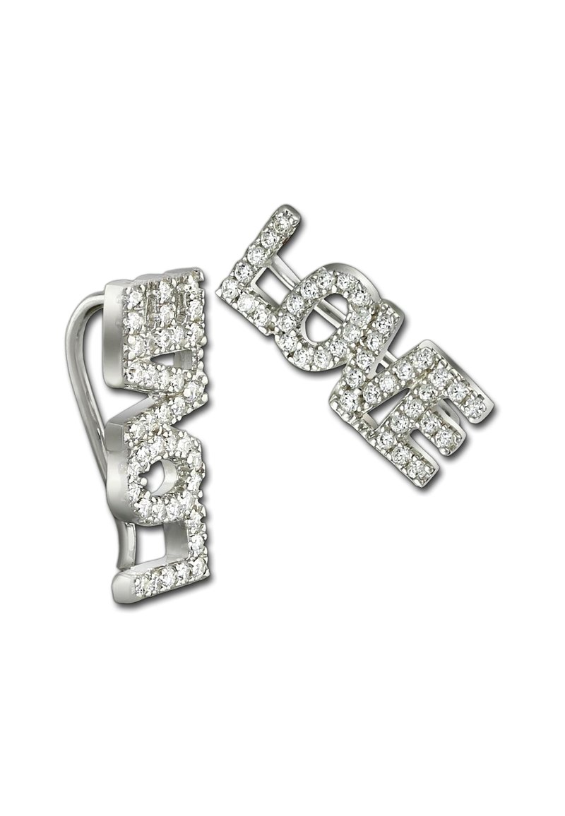 Une paire de boucles d'oreilles en argent épelant "AMOUR" entourée de petites cristaux transparents sur un fond blanc.