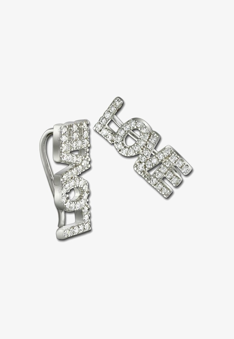 Une paire de boucles d'oreilles en argent épelant "AMOUR" entourée de petites cristaux transparents sur un fond blanc.