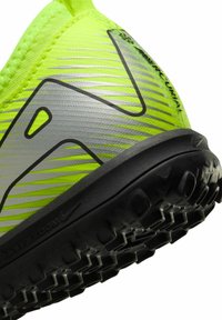 Baskets de sport jaunes vives avec une tige texturée, ornées d'accents argentés et d'une semelle en caoutchouc noir avec des rainures de traction prononcées.