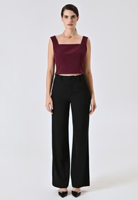 Top corto bordeaux con scollatura quadrata abbinato a pantaloni neri a gamba larga. Tessuto liscio con dettagli minimi, completato con scarpe nere a punta.
