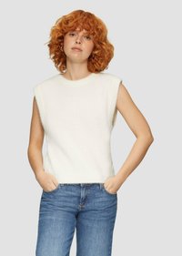 Haut tricoté sans manches blanc avec un col rond, présentant une texture douce et une coupe légèrement courte, associé à un jean en denim bleu.
