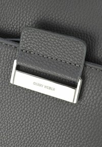 Sivka teksturirana usnjena torbica z metalnim zapiranjem, na katerem je vgravirano ime blagovne znamke "GERRY WEBER" na srebrnem akcentu.