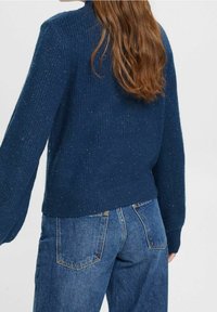 Marineblauer Pullover mit Rippstruktur, langen Ärmeln und gekürztem Saum. Gepaart mit blauen Jeans, Rückansicht.