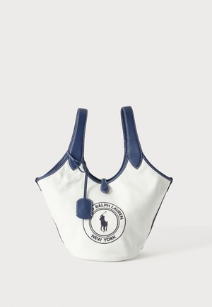 Biała torba typu tote z płótna z granatowymi uchwytami i obwódką, z naszywką z logo Ralph Lauren na przodzie oraz małą zawieszką.