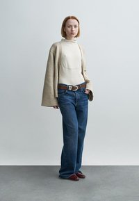 Μπεζ πλεκτή oversized ζακέτα, κρεμ εφαρμοστό τοπ, μπλε παντελόνι με φαρδιά μπατζάκια, καφέ ζώνη με ασημένια αγκράφα και μπορντό παπούτσια. Απλό, μοντέρνο σύνολο.