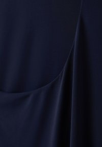 Tissu bleu marine foncé avec des plis doux et une texture lisse créant des lignes courbes fluides.