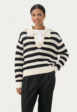 Pull rayé noir et crème, avec un col en V et un col en tricot ouvert. Les poignets et l'ourlet côtelés apportent de la structure.