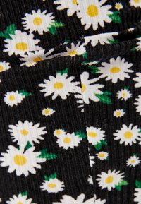 Una tela negra texturizada con rayas verticales presenta un patrón disperso de margaritas blancas con centros amarillos y hojas verdes.