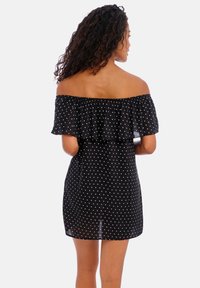 Vestido preto com decote à barbarico e babados, apresentando um padrão de bolinhas e uma silhueta ajustada, com comprimento até metade da coxa.