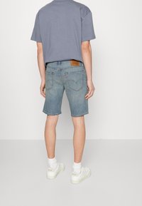 Ljusblå denimshorts med rak skärning, uppvikta fållar och två bakfickor. Matchat med en luftig grå t-shirt och vita sneakers.