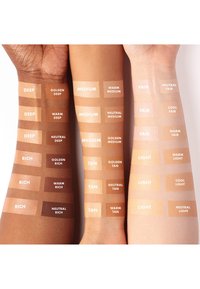 Cuatro brazos con muestras de piel exhiben diversos tonos: oscuro, medio, bronceado, claro, con etiquetas en texto blanco para la identificación del color.