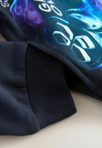 Dunkelblaues Sweatshirt mit einem glatten Grafikdesign in Blau- und Lilatönen, mit gerippten Bündchen und einem detaillierten Druck auf der Vorderseite.