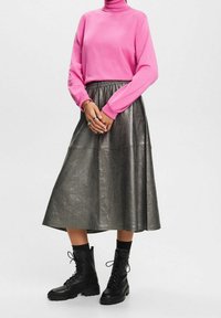 Magenta coltrui, glanzende grijze midi-rok en zwarte veterschoenen met volle zool. Textuurstof en een geraffineerde tailleband op de rok.