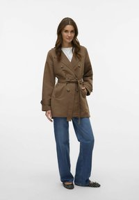 Brun, dubbelknäppt trenchcoat med knytbälte, stora knappar och sidofickor. Tillsammans med vida denimjeans och svarta ballerina.