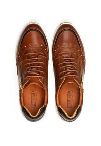 Par de zapatillas casuales de cuero marrón con cordones, cremalleras laterales y acentos en negro en el talón sobre fondo blanco.