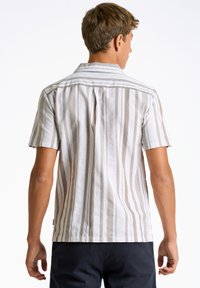 Camisa de manga corta en beige claro y blanco con rayas verticales, cuello abotonado y detalle de pliegue en la parte posterior. Material de algodón.
