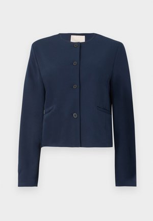Veste col montant à manches longues bleu marine, sans col, avec quatre boutons noirs et deux poches latérales fentes, coupe ajustée.