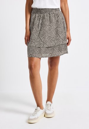 Grå kjol med ett texturerat zebramönster, elastisk midja och lagerdesign. Stylerad med vita sneakers för en avslappnad look.