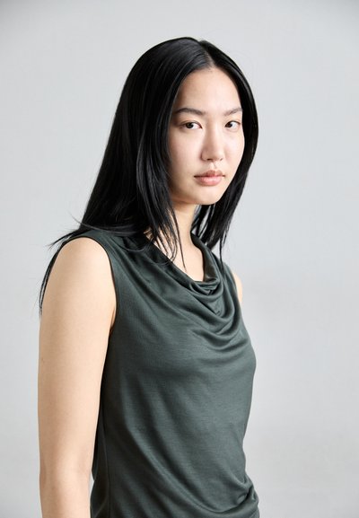Green sleeveless top with a cowl neck design, made of soft fabric, featuring a smooth texture and a fitted silhouette.