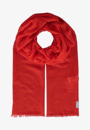 Bufanda de tejido suave de color rojo brillante con bordes con flecos y una pequeña etiqueta de marca en una esquina, doblada cuidadosamente en forma de lazo.