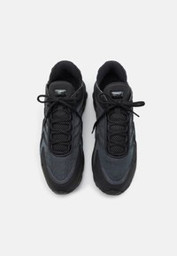 Chaussures de sport noires avec empeigne en maille et synthétique, bout rond, col rembourré et lacets. Elles présentent une semelle en caoutchouc et des accents de logo.