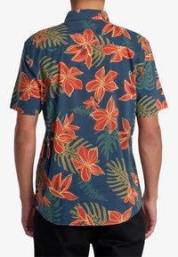 Short-sleeve shirt made of fabric featuring a blue background, vibrant red and orange floral patterns, and green leaf accents.